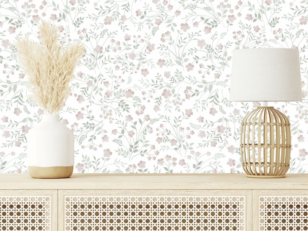 Blommig rosa tapet bakom träbänk med vas och lampa.