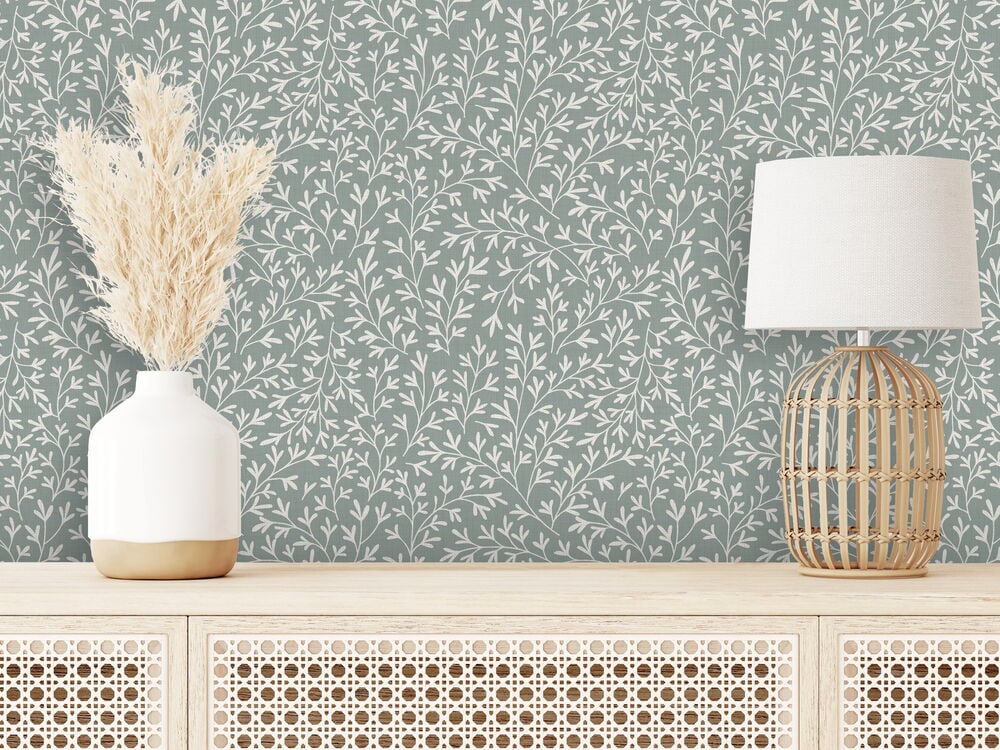 Grön tapet med vitt rankmönster bakom sideboard.