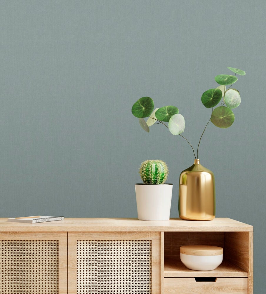 Grön linnetapet bakom träskåp med växter.