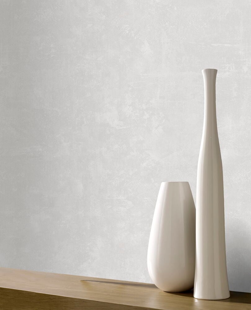 Två vita vaser framför greige tapetvägg.