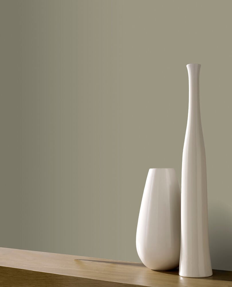 Matt grön enfärgad tapet bakom två vita vaser.