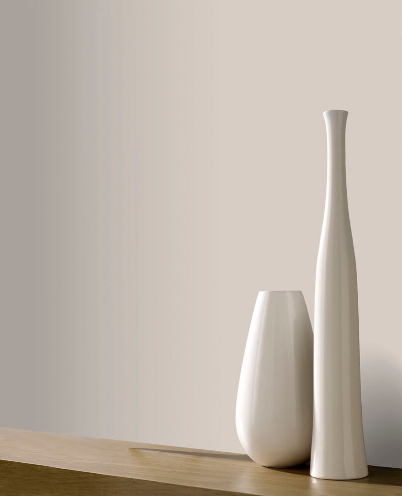 En slät greige tapet bakom vita vaser.
