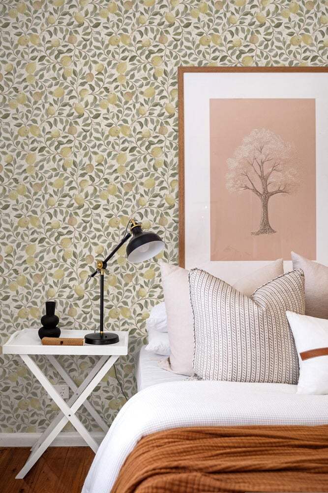 Gulmönstrad tapet med citroner bakom säng och nattduksbord.