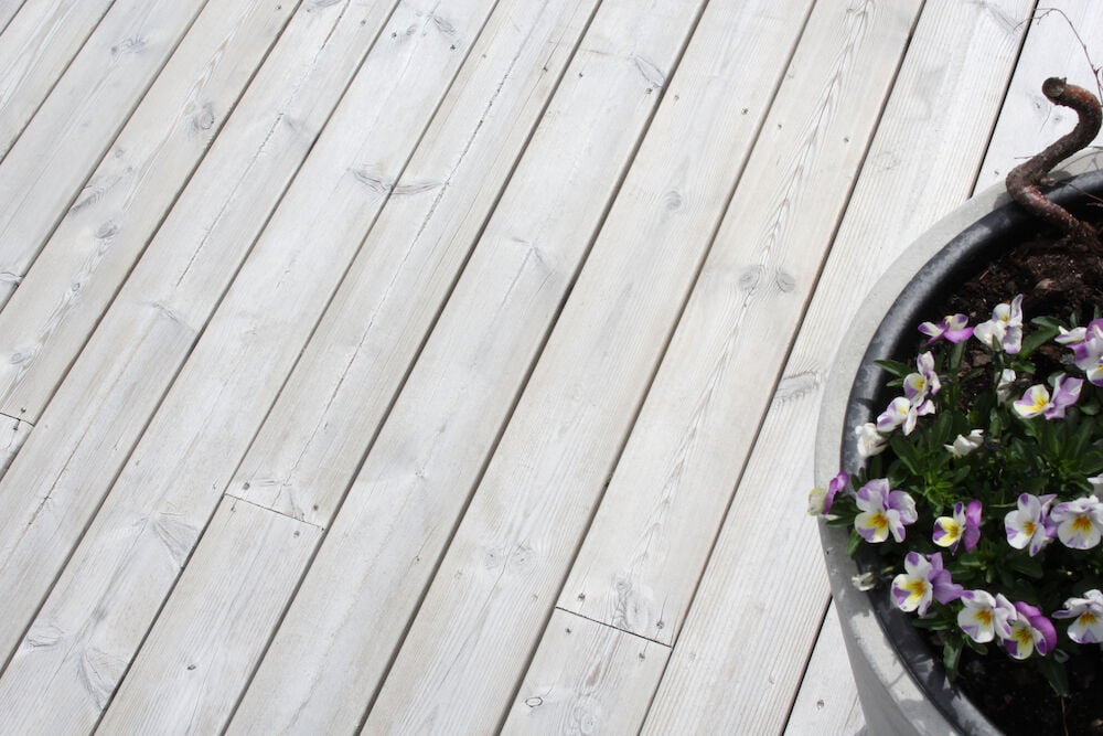 Ljust behandlat trädäck med silvergrå finish och blomkruka.
