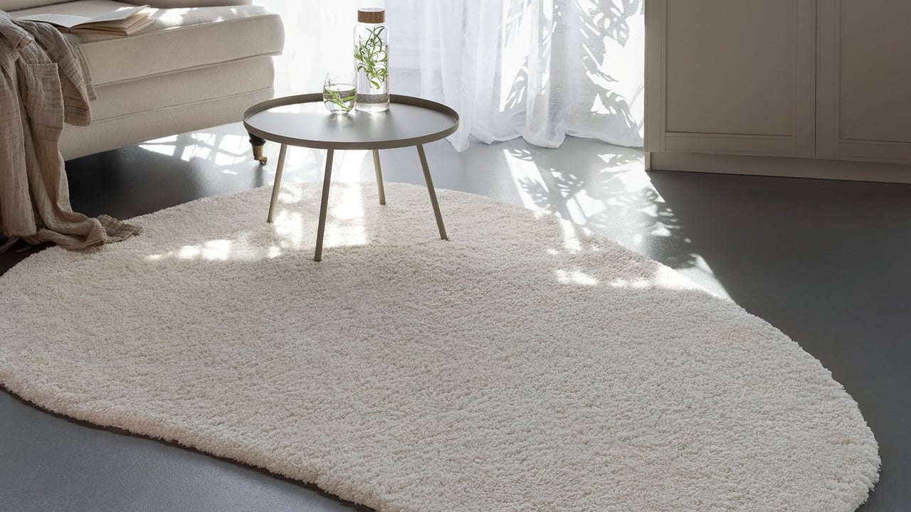 Vardagsrum med soffa, sidobord och en ljus matta med struktur.