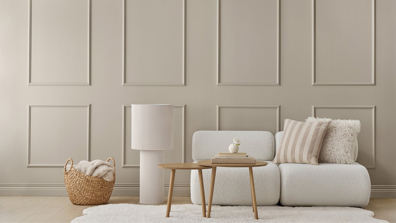 Wohnzimmer mit grau-beigen Wänden und Zierleisten.