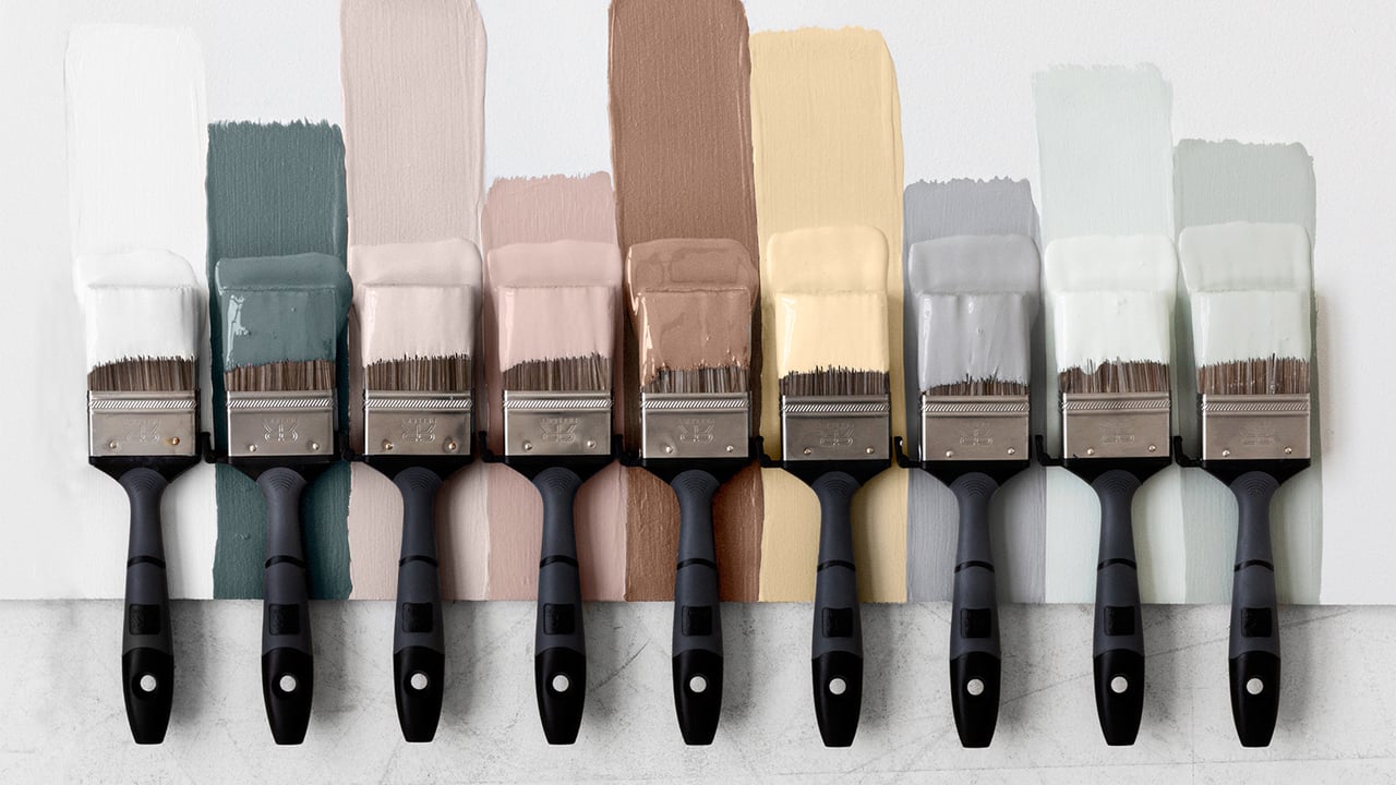 Erilaisiin maalipurkkeihin kastetut siveltimet rivissä vierekkäin.