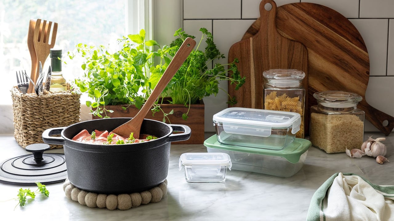 Paljon ruokaa kattilassa keittiön työtasolla, jossa on eväsrasioita ja keittiötarvikkeita.