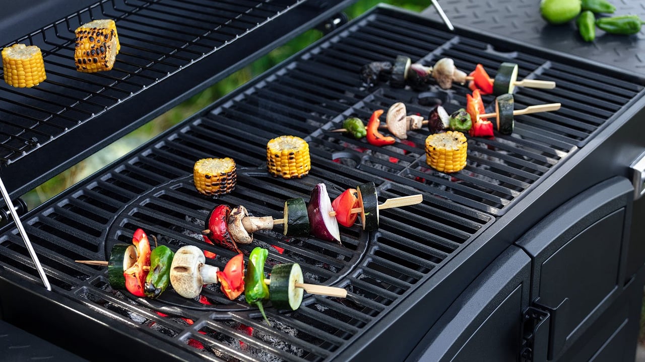 Närbild på grillhäll där det ligger ett antal spett med grönsaker.