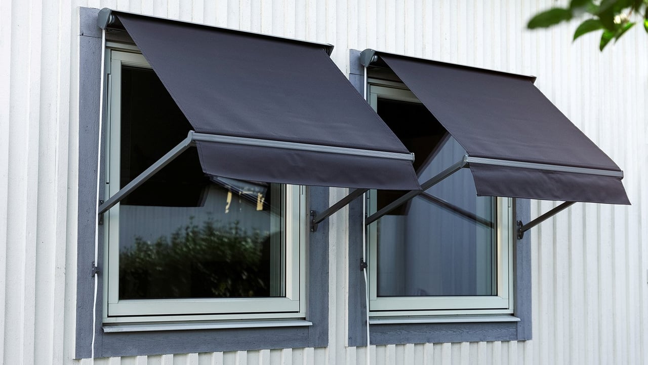 Kaksi valkoiseksi maalatun omakotitalon ikkunaa, joissa on avatut merensiniset markiisit.