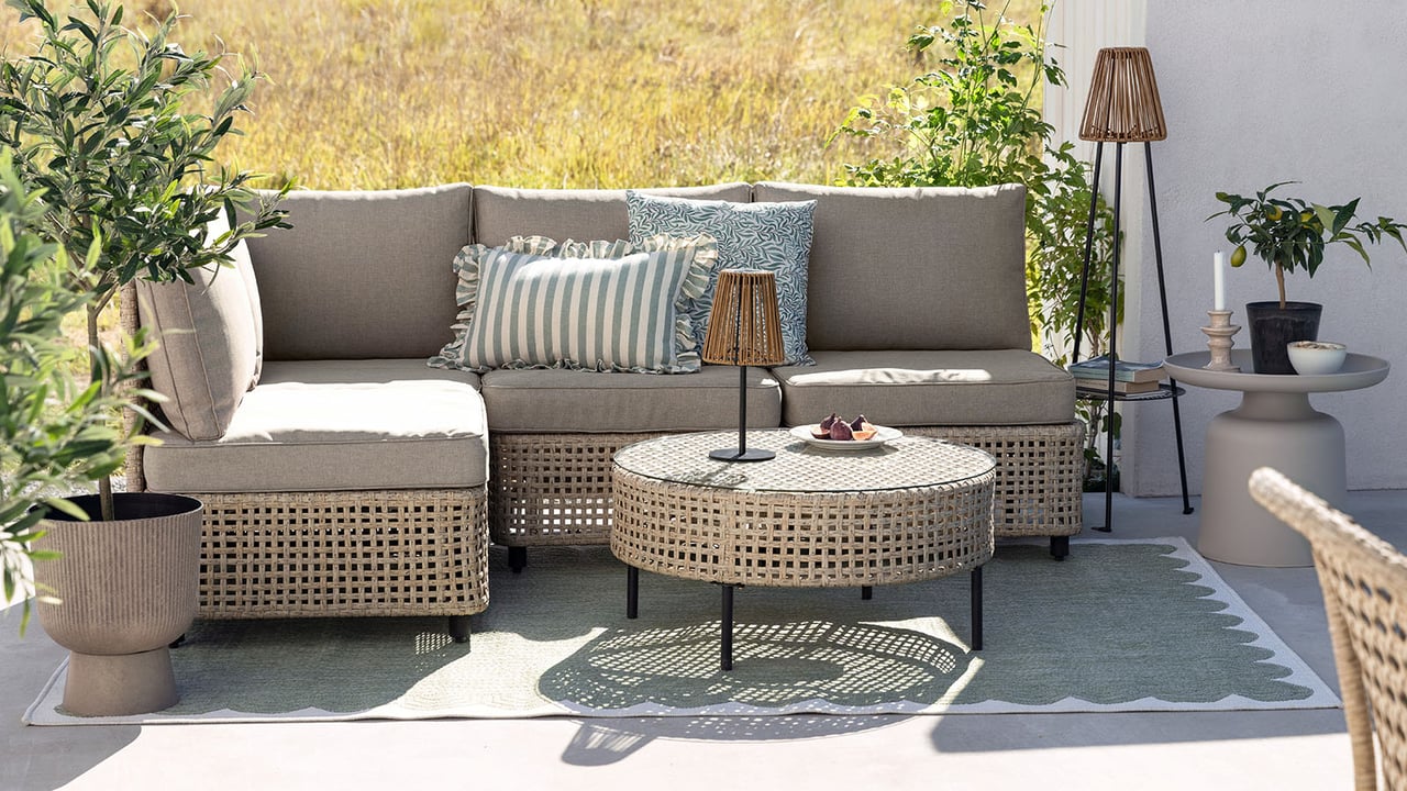 Uteplats med beige loungegrupp och tillhörande bord.