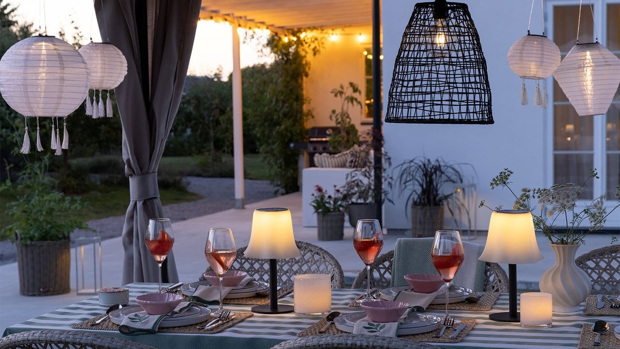 Terassi, jossa katettu pöytä ja aurinkokennovalaisimia pöydällä ja katosta ripustettuna.