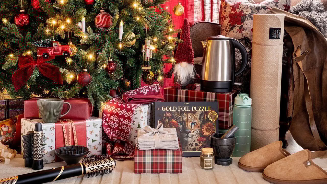 Julgran med tända ljus omgiven av inslagna paket och julklappstips.