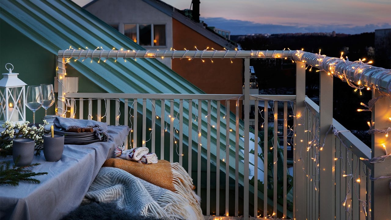 Ljusslingor virade runt balkongräcke i skymning och vintrig miljö.
