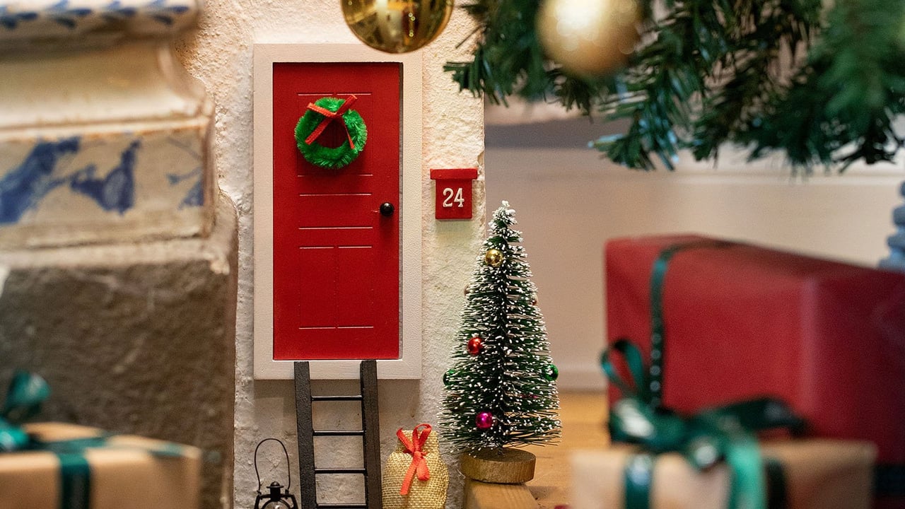 Nissedør med stige, mini-juletre og postkasse festet på en vegg plassert ved gulvlist.