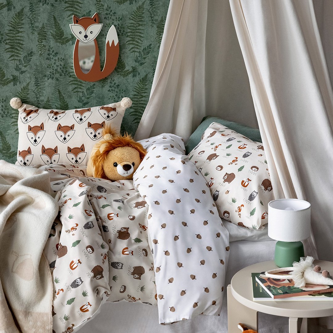 Säng i ett barnrum. Sängkläder med djurmönster, beige sänghimmel och spegel formad som en räv.